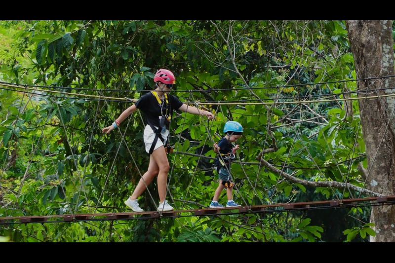 A visitor soaring through the treetops on a zipline at Hanuman World Phuket, enjoying an exhilaratin